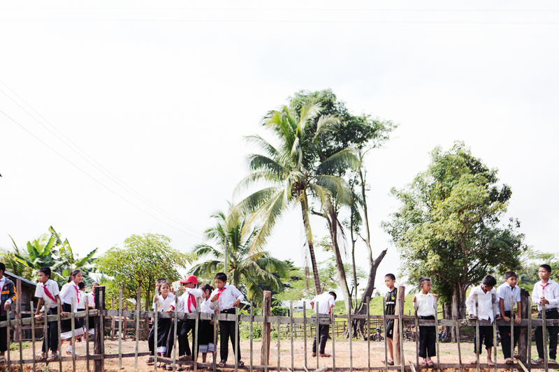 Schoolchildren look on as the elephants take over their schoolyard for a midday break and lunch. While the elephants are eating, the kids got to look on and learn about what makes elephants so unique and important.Tara Rice Photography